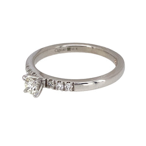 Preowned 9ct White Gold & Diamond Set Clogau Solitaire Ring in size O with the weight 2.60 grams. The center diamond is approximately 20pt and the shoulders are set with diamonds. The diamonds are approximate clarity VS2 - Si1 and colour K - M