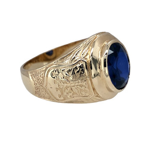 Preowned 9ct Yellow Gold & Blue Stone Set University Style Signet Ring in size Z+3 with the weight 9.60 grams. The front of the ring is 19mm high and the blue stone is approximately 12mm by 10mm. The shoulders of the ring have bird on one shoulders and a shield shaped crest on the other