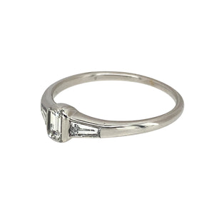 Preowned 18ct White Gold & Diamond Set Emerald Cut Solitaire Ring in size O with the weight 2.30 grams. The center diamond is emerald cut and there are two tapered baguette diamonds set on the shoulders