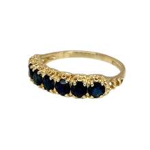 Load image into Gallery viewer, Add a touch of timeless elegance to your jewellery collection with this pre-owned 9ct yellow gold &amp; sapphire set band ring, featuring:

Design: A classic band ring, adorned with a row of beautiful sapphires for a refined and sophisticated look.
Material: 9-carat yellow gold, offering a warm and enduring appeal.
Gemstones: Set with seven sapphires, each approximately 4mm in diameter, providing a rich and vibrant blue hue.
Size &amp; Weight: Designed in size O, with a well-balanced weight of 2 grams for a comfort
