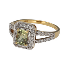 Load image into Gallery viewer, Preowned 18ct Yellow and White Gold Diamond &amp; Light Green/Yellow Stone Set Halo Ring in size S with the weight 4.30 grams. The ring has a diamond set split shoulder and the stone is possibly a beryl. The green stone is 7mm by 5mm
