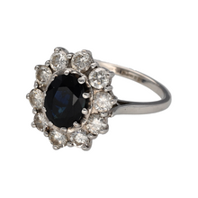 Load image into Gallery viewer, Preowned 18ct White Gold Diamond &amp; Sapphire Set Cluster Ring in size O with the weight 5.90 grams. The front of the ring is 18mm high and the sapphire stone is 9mm by 7mm. There is approximately 1.10ct of diamond content in total
